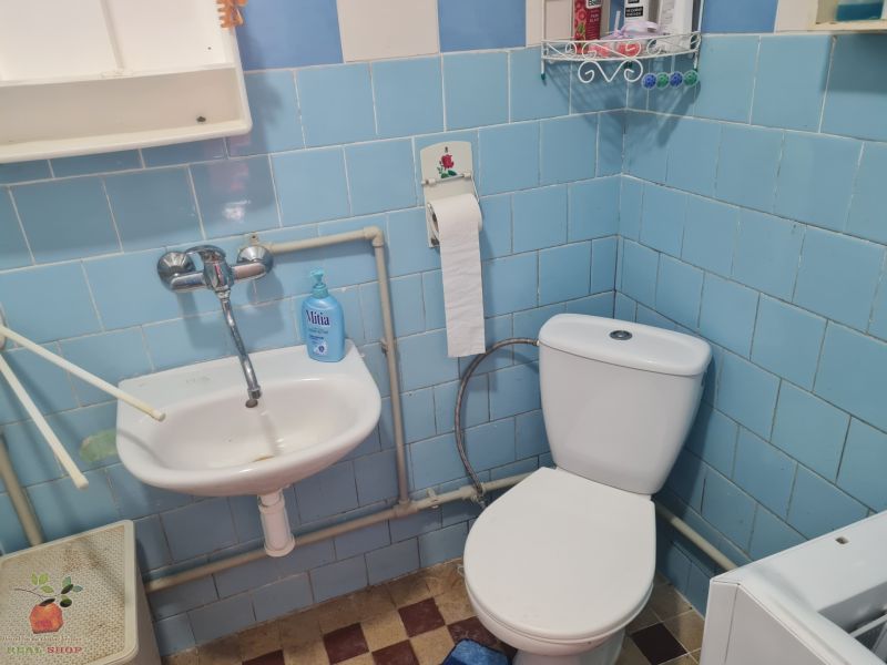 A bathroom in a family house with blue tiles, a sink, and a toilet.
