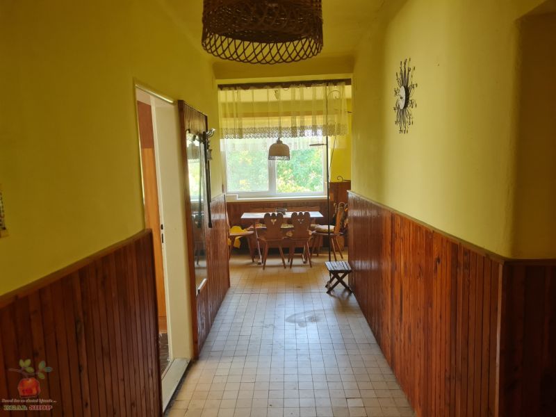 A hallway in a family house with wooden paneling and a view of the dining area.
