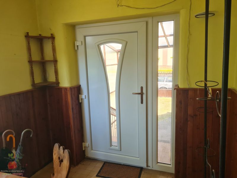 Entrance door in a family house with wooden paneling and tiled floor.