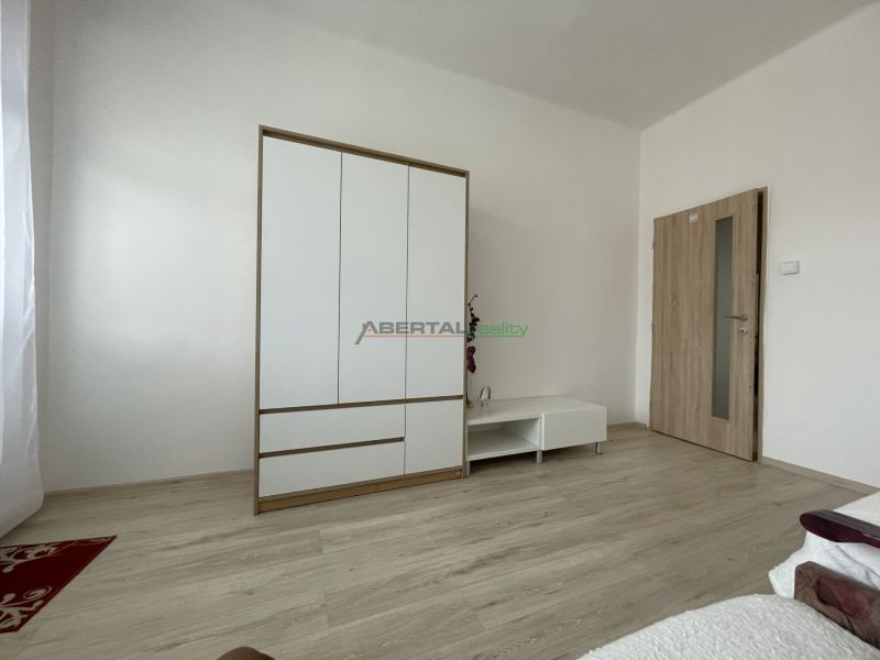 White wardrobe and furniture in a room with wood-patterned flooring in a 3-room apartment.