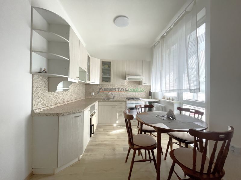 A kitchen in a 3-room apartment with a table and chairs, a floor with a wooden decor.