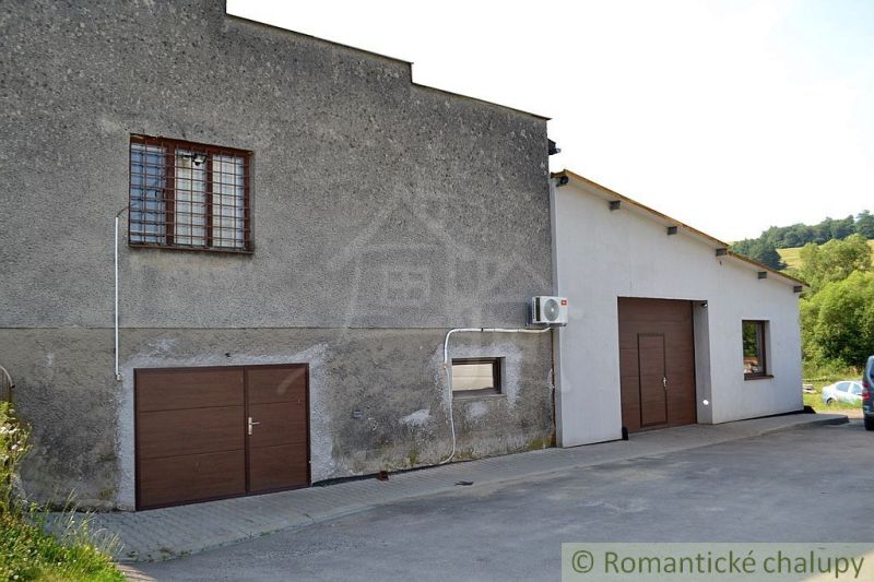 The exterior of a family house in Varadka with a garage door and a window with an anti-burglary screen.