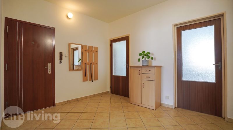 A hallway with tiles, wooden doors, a mirror, and a dresser in a 3-room apartment.
