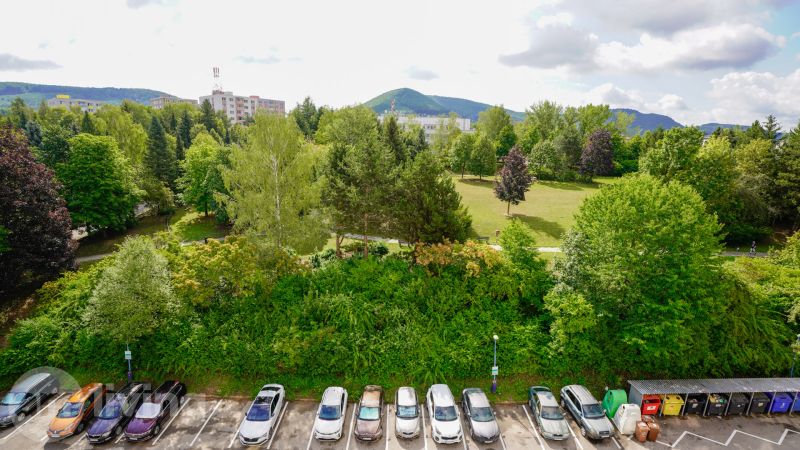View from a 3-room apartment in Dubnica nad Váhom on Pod Hájom street overlooking greenery and a parking lot.
