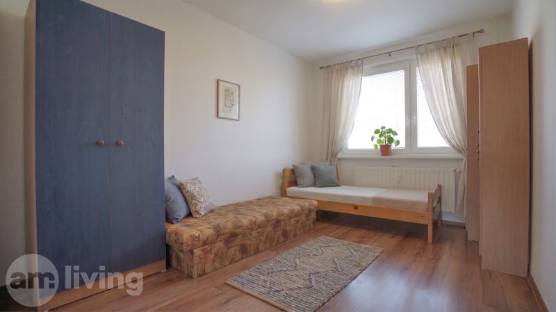 A room in a 3-room apartment with a bed, a wardrobe, and a floor with a wooden decor.