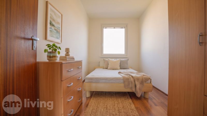 Cozy bedroom in a 3-room apartment with a bed, dresser, and wooden decor flooring.