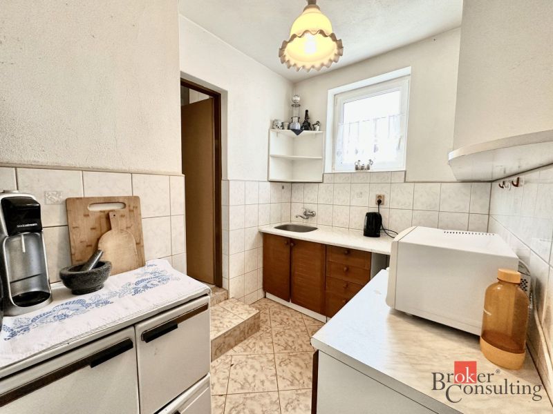 A kitchen in a family house with white tiles and appliances on the counter.