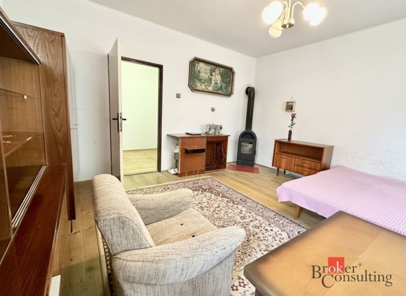 Living room in a family house with tiled stove, furniture, and wooden decor flooring.