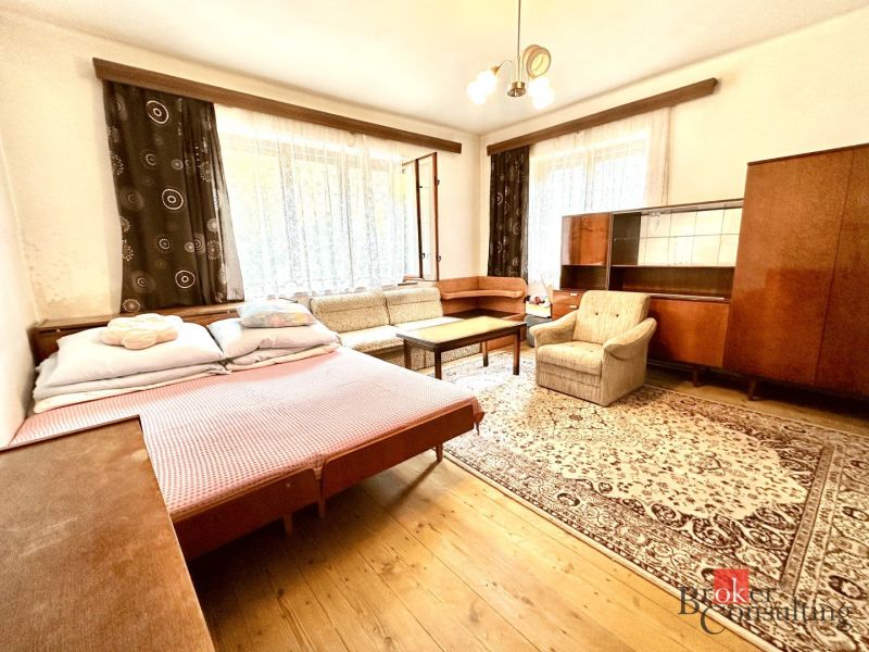 A room with a sofa and an armchair, a floor with a wooden decor, a carpet, furniture.