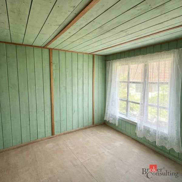 A room in a family house with wooden wall paneling and a large window.