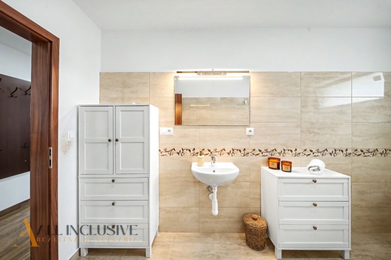Bathroom in a family house with a sink, mirror, and white furniture.