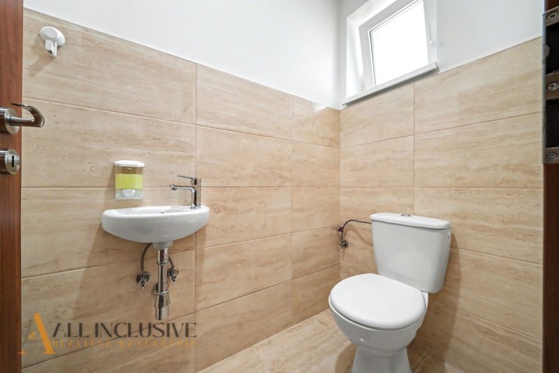 A bathroom in a family house with light tiles and a small sink.