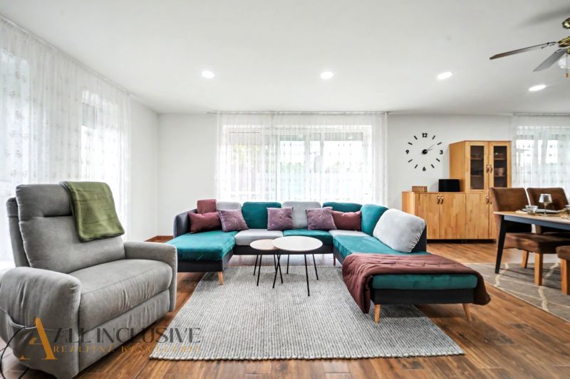 Living room with a sofa, armchair, and wood-patterned flooring in a family house.