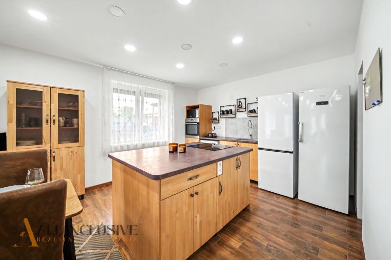 A kitchen in a family house with wooden decor, white appliances, and an island.