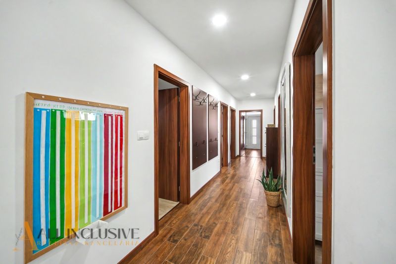 A hallway in a family house with a wooden decor floor and a colorful wall piece.