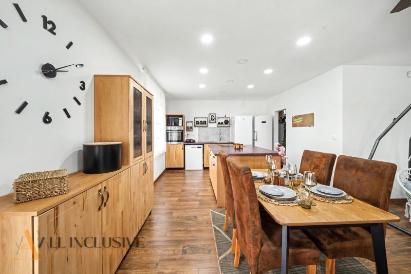 A dining room with wooden decor, a wall clock, and an elegantly set table in a family house.