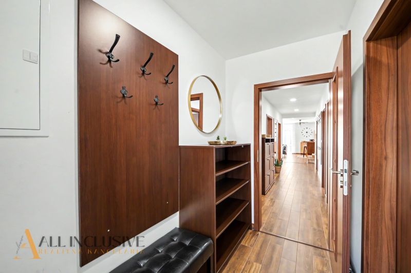 A hallway in a family house with a mirror, hooks, and a wooden decor floor.