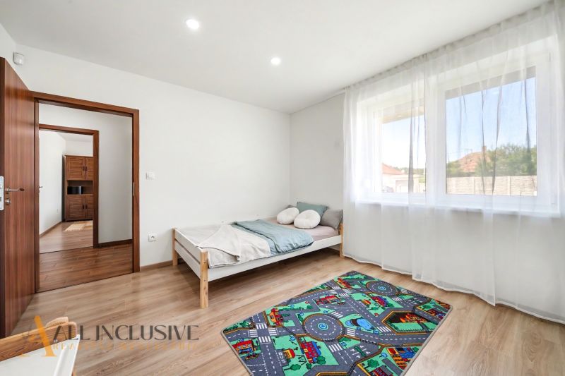 A bright room in a family house with a wooden decor floor and a children's carpet.