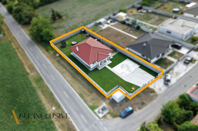A family house in Vozokany with a red roof, a garden, and a concrete yard along the road.