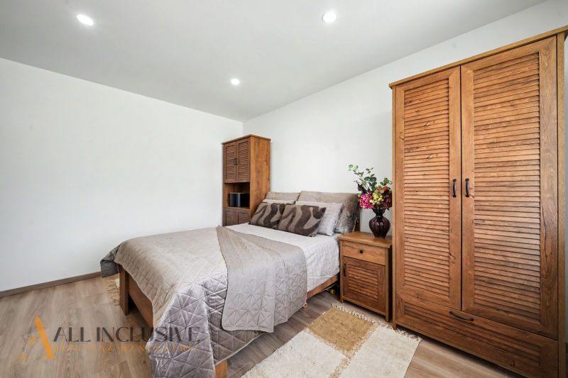 A bedroom in a family house with a wooden decor floor and wooden furniture.