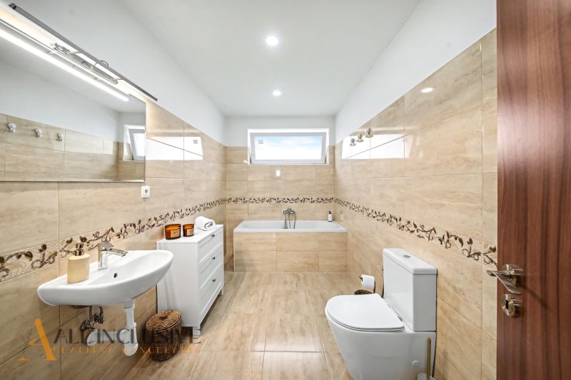 A bathroom in a family house with a bathtub, tiles, and a toilet.
