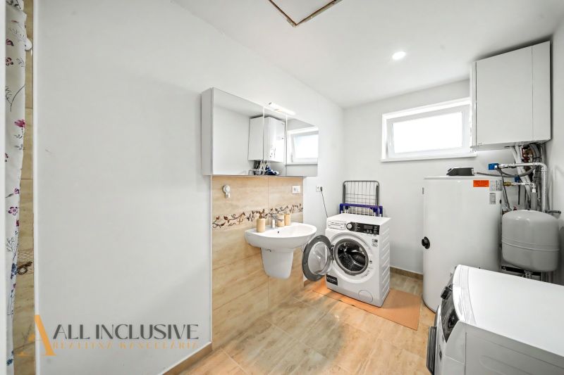 A bathroom in a family house with a washing machine, dryer, and white cabinets.