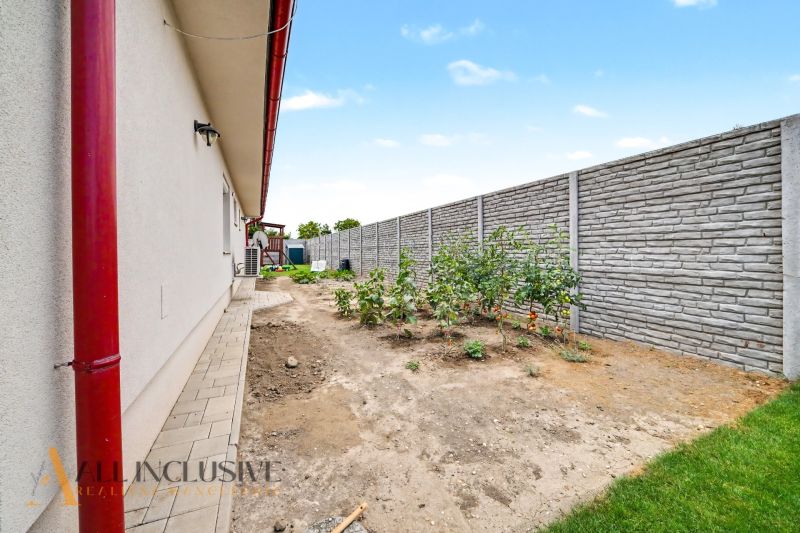 The garden of a family house in Vozokany with a wall, paving, and plants.