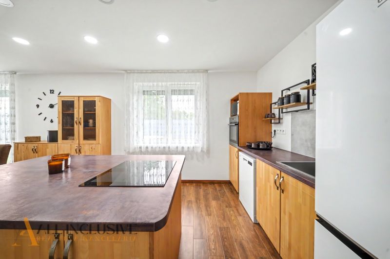 A kitchen with an island and a wooden decor floor in a family house.