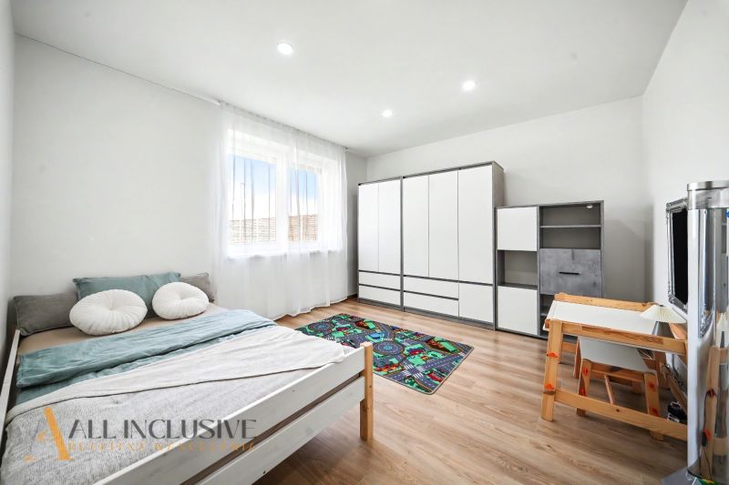 A room with a bed, a desk, a wardrobe, and a wooden-patterned floor.
