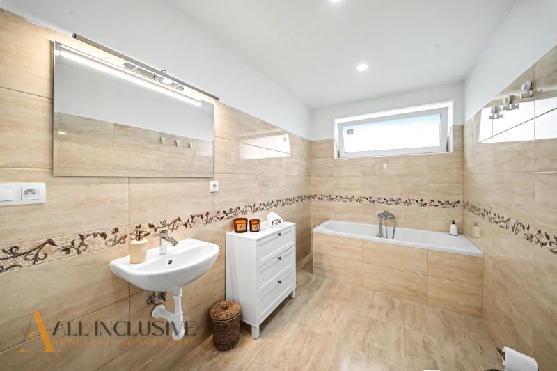 A bathroom in a family house with a bathtub, a mirror, and a white sink.