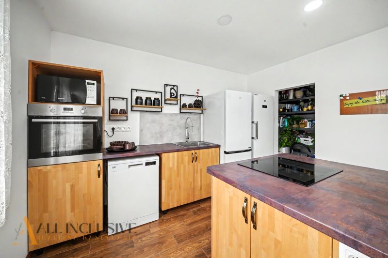 A kitchen in a family house with white appliances, wooden decor, and modern equipment.