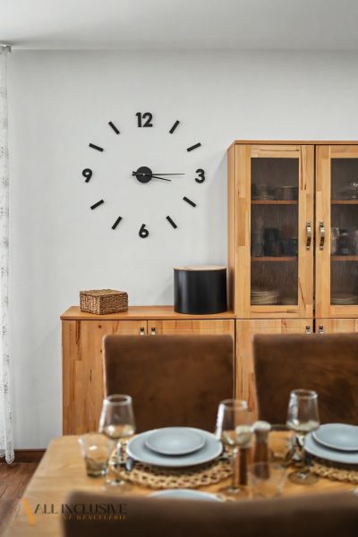 Dining room in a family house with a clock on the wall and wooden furniture.