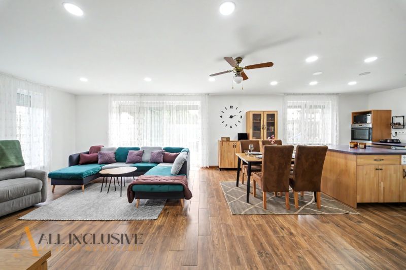 Living room in a family house with wood-patterned flooring, a sofa set, and a dining table.