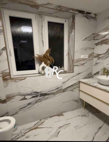A bathroom in a 2-room apartment with marble tiles and large windows.