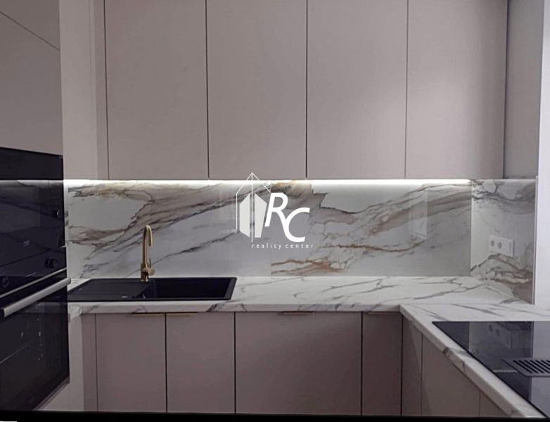 A kitchen in a 2-room apartment with a marble countertop and a black sink.