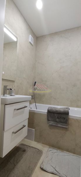 A bathroom in a 3-room apartment with a bathtub and storage cabinets.