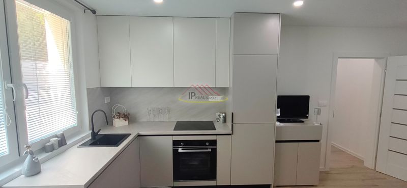 A kitchen in a 3-room apartment with a wooden decor floor and modern cabinets.