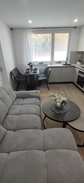 Living room with kitchen and dining area, 3-room apartment with wooden decor flooring.