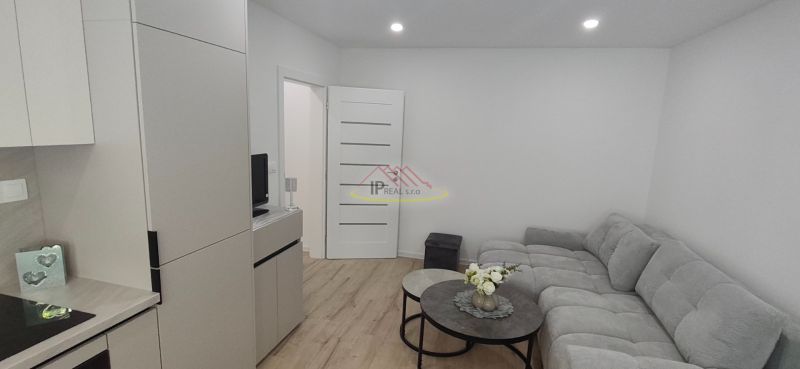 Living room in a three-room apartment with a sofa, tables, and a wooden decor floor.