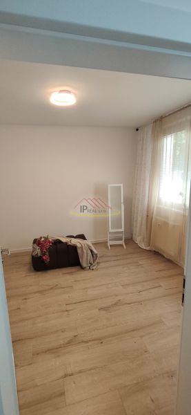 A room with a wooden floor decor, a pouf, and a lamp in a three-room apartment.