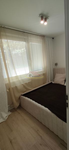 A bright interior of a 3-room apartment with a bed and wooden decor flooring.