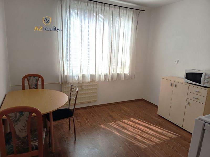 A dining room in a one-room apartment with a wood-patterned floor, table, and furniture.