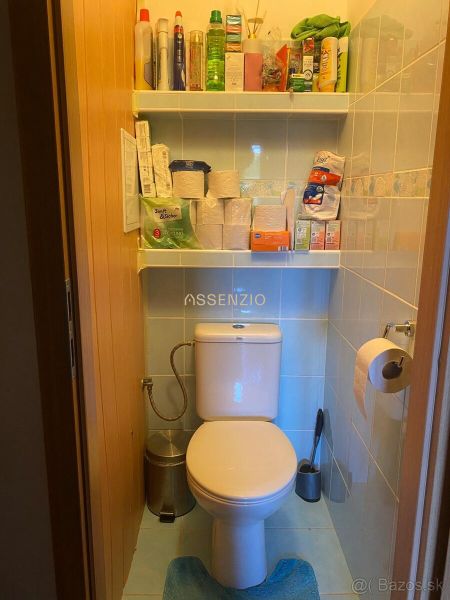 A small bathroom in a two-room apartment with a toilet and shelves for toiletries.