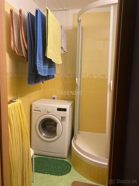A bathroom with a washing machine and a shower in a 2-room apartment.