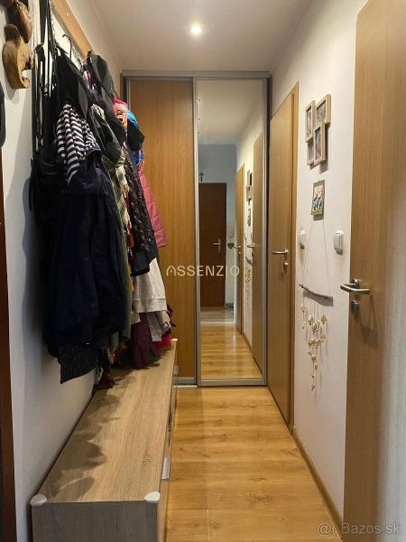A hallway in a 2-room apartment with coat racks and a mirrored wardrobe, flooring with a wooden decor.