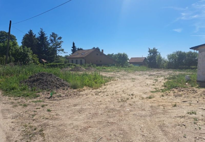 A plot of land for living in Láb with buildings surrounded by greenery and a clear sky.