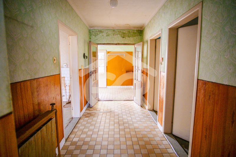 A hallway in a family house with wall cladding and a tiled floor.