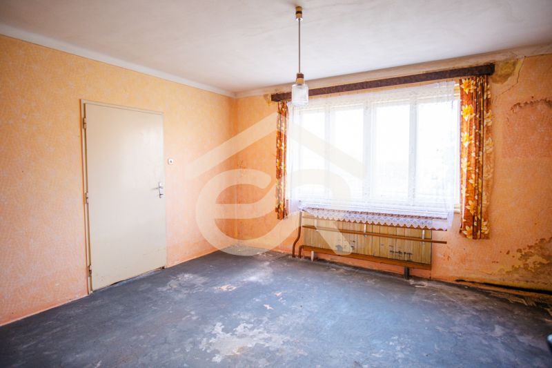 A room in a family house with a worn-out carpet, a window, and curtains.