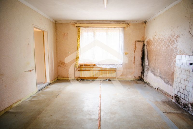 The interior of a family house with peeling wallpaper, neglected walls, and old tiles.
