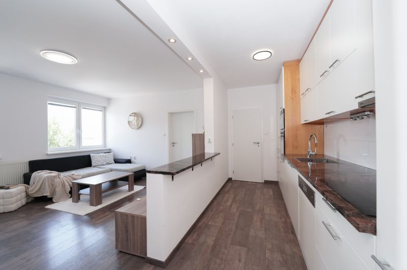 Living room and kitchen in a 3-room apartment, with a wooden decor floor.